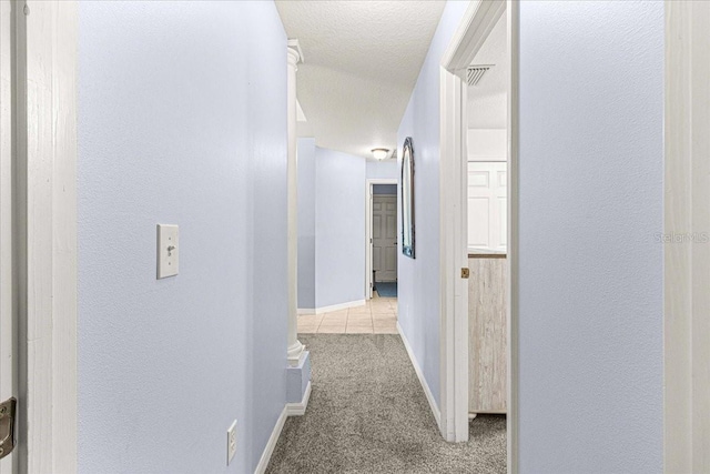 hall with light carpet and a textured ceiling