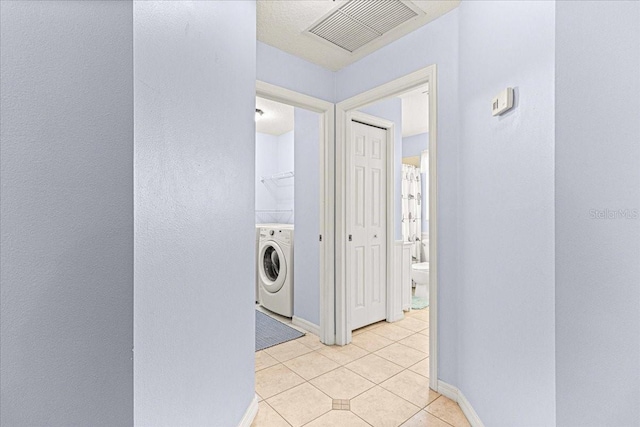 laundry area featuring washer / dryer and light tile patterned flooring