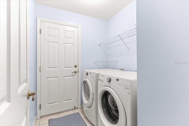 laundry room featuring light tile patterned floors, a textured ceiling, and washing machine and clothes dryer