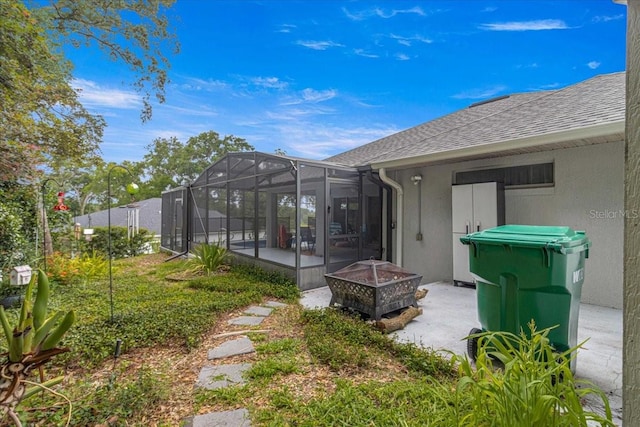 rear view of house featuring glass enclosure and an outdoor fire pit