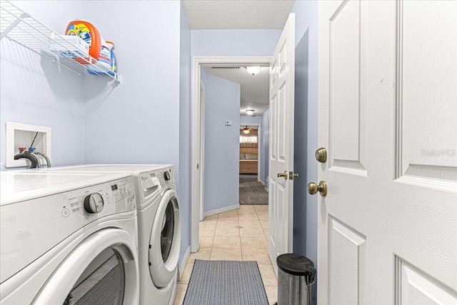 clothes washing area with separate washer and dryer, ceiling fan, light tile patterned floors, and a textured ceiling