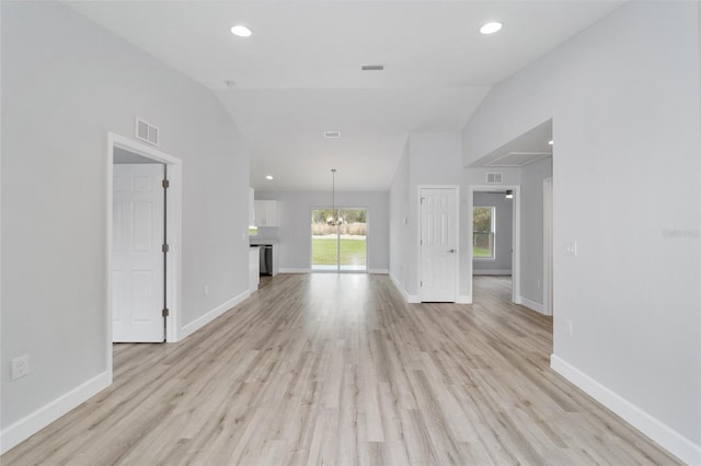 unfurnished living room featuring a chandelier, lofted ceiling, and light wood-type flooring