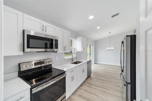 kitchen featuring decorative light fixtures, light wood-type flooring, white cabinets, sink, and appliances with stainless steel finishes