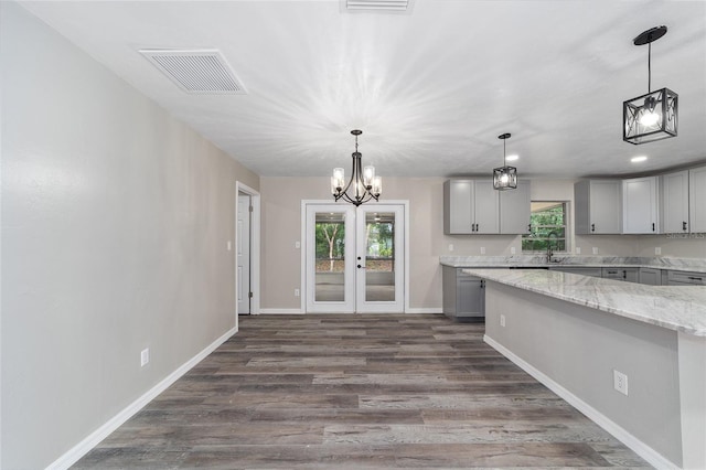 kitchen featuring light stone countertops, gray cabinetry, dark hardwood / wood-style floors, and plenty of natural light