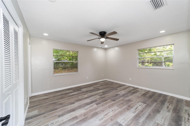 unfurnished bedroom featuring multiple windows, hardwood / wood-style flooring, and ceiling fan