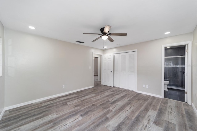 unfurnished bedroom featuring connected bathroom, hardwood / wood-style floors, and ceiling fan