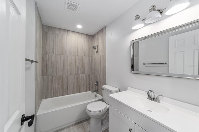 full bathroom featuring vanity, hardwood / wood-style flooring, tiled shower / bath, and toilet