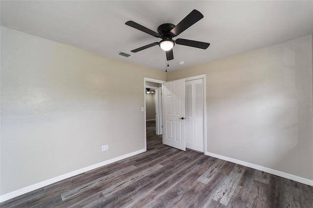 unfurnished bedroom featuring dark hardwood / wood-style flooring, ceiling fan, and a closet