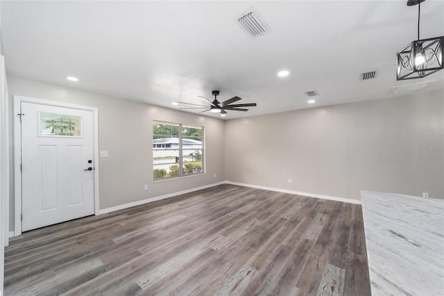 interior space with ceiling fan with notable chandelier and dark hardwood / wood-style flooring