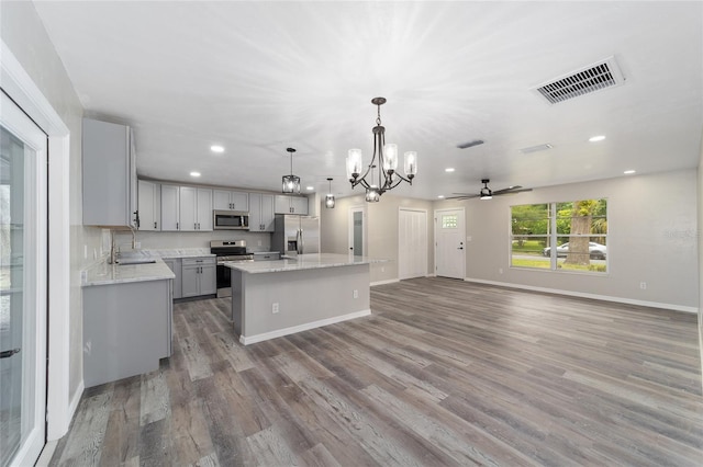 kitchen featuring pendant lighting, a kitchen island, gray cabinetry, appliances with stainless steel finishes, and hardwood / wood-style floors