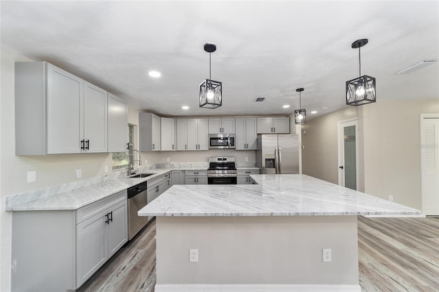 kitchen featuring hanging light fixtures, a large island, gray cabinets, appliances with stainless steel finishes, and light hardwood / wood-style floors