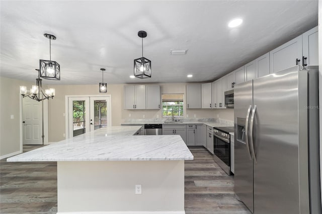 kitchen featuring dark hardwood / wood-style floors, pendant lighting, stainless steel appliances, and a wealth of natural light