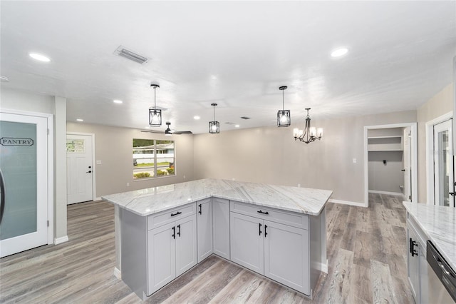 kitchen with light stone countertops, hanging light fixtures, a kitchen island, and stainless steel dishwasher