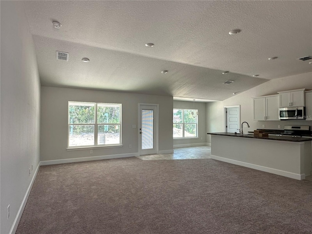 unfurnished living room featuring a textured ceiling, vaulted ceiling, sink, and light carpet