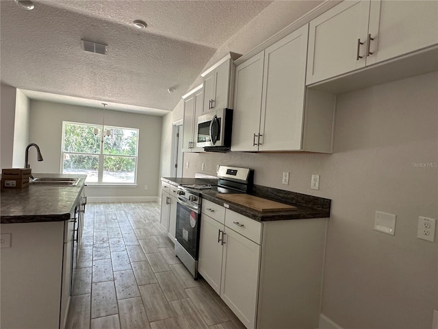 kitchen featuring appliances with stainless steel finishes, white cabinetry, and sink