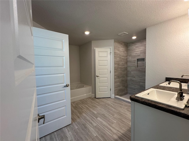 bathroom featuring vanity, a textured ceiling, wood-type flooring, and independent shower and bath