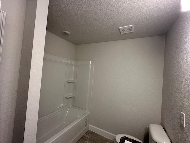 bathroom with visible vents, toilet, a textured ceiling, wood finished floors, and baseboards