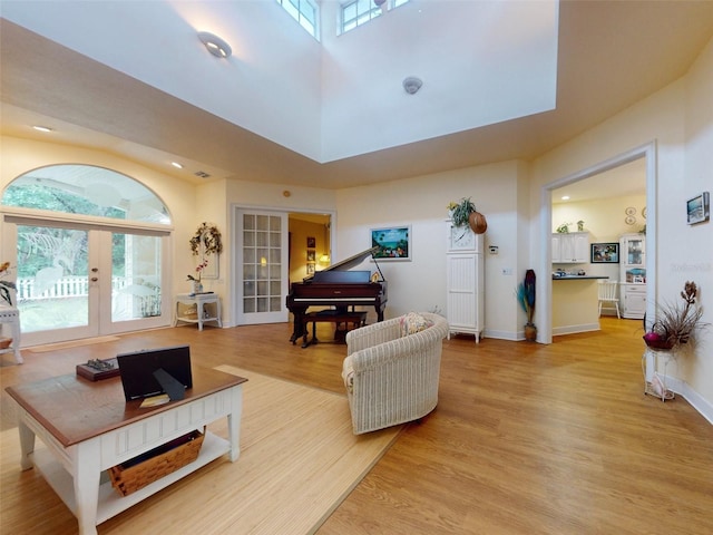 living room featuring a towering ceiling, french doors, and light wood-type flooring