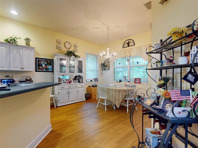 kitchen with white cabinetry, hanging light fixtures, light hardwood / wood-style floors, and an inviting chandelier