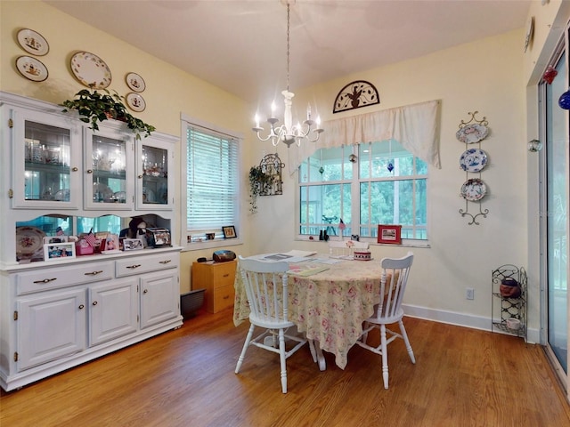 dining space with light hardwood / wood-style flooring and an inviting chandelier