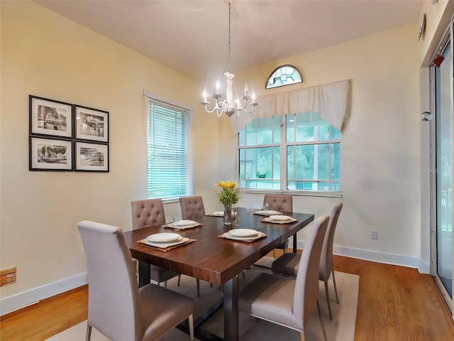 dining room with a healthy amount of sunlight, wood-type flooring, and an inviting chandelier