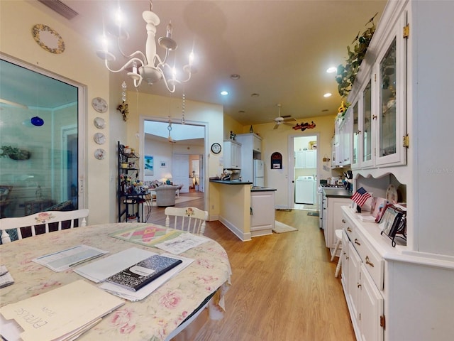 dining room with ceiling fan with notable chandelier, washer / dryer, and light hardwood / wood-style flooring