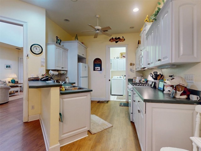 kitchen featuring kitchen peninsula, white appliances, light hardwood / wood-style flooring, white cabinets, and washer / clothes dryer