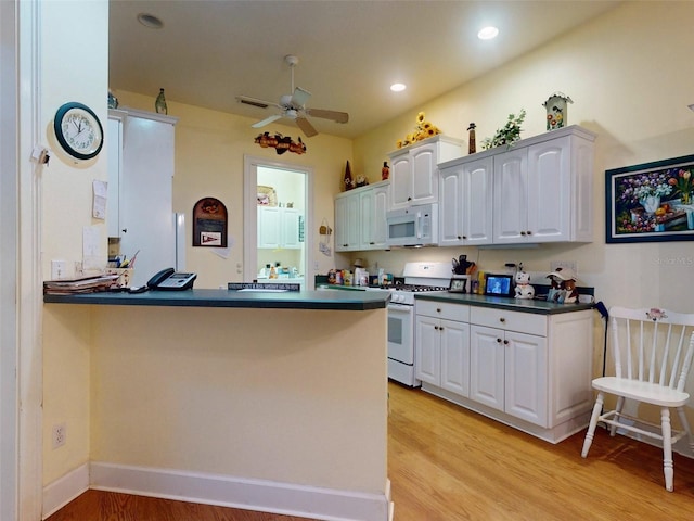 kitchen with light hardwood / wood-style floors, white cabinetry, white appliances, and kitchen peninsula