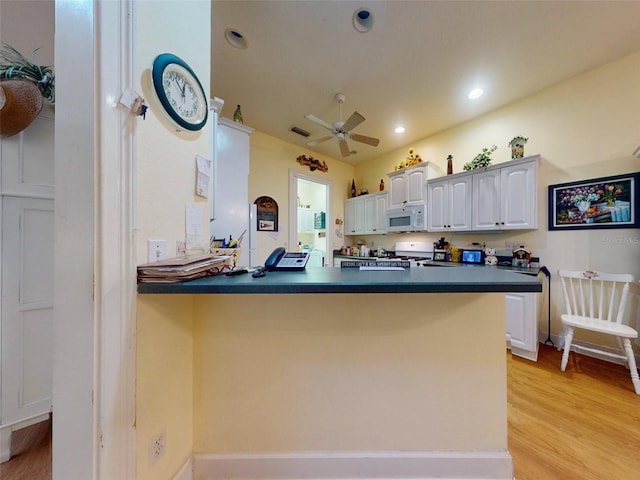 kitchen featuring kitchen peninsula, light wood-type flooring, white appliances, ceiling fan, and white cabinets