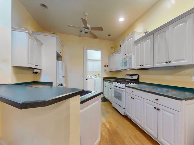 kitchen featuring white cabinetry, light hardwood / wood-style flooring, washer and dryer, and white appliances