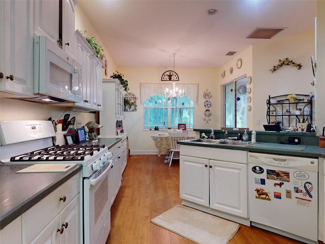 kitchen featuring white appliances, sink, decorative light fixtures, an inviting chandelier, and white cabinetry