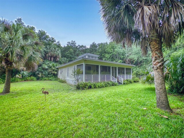 view of front of property featuring a sunroom and a front lawn