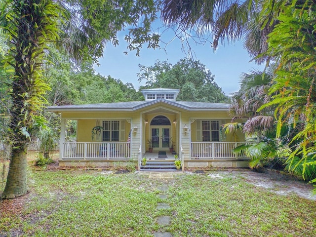 view of front of property featuring french doors, a front lawn, and covered porch