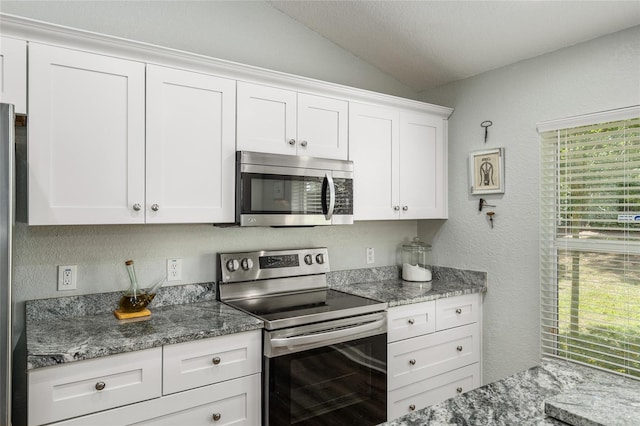 kitchen featuring white cabinetry, vaulted ceiling, stone countertops, and appliances with stainless steel finishes