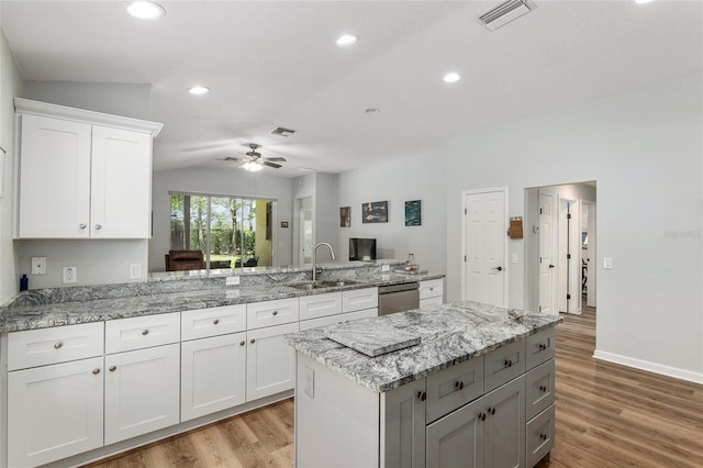 kitchen featuring sink, light hardwood / wood-style flooring, dishwasher, white cabinetry, and kitchen peninsula