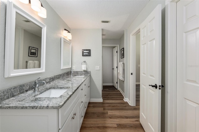 bathroom with wood-type flooring, a textured ceiling, and vanity