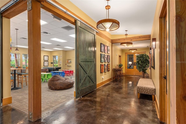 corridor featuring a paneled ceiling and a barn door