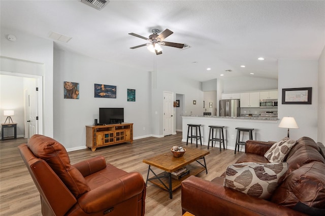 living room with lofted ceiling, ceiling fan, and light wood-type flooring