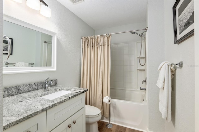 full bathroom with hardwood / wood-style floors, shower / bath combination with curtain, vanity, toilet, and a textured ceiling