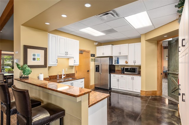 kitchen with stainless steel appliances, white cabinetry, sink, and kitchen peninsula