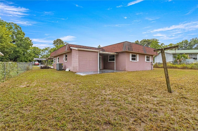 rear view of house featuring a lawn, a patio, and central air condition unit