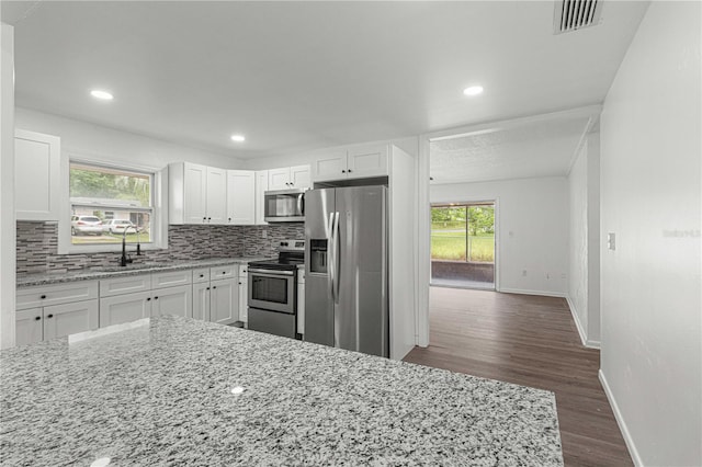 kitchen featuring white cabinetry, appliances with stainless steel finishes, dark hardwood / wood-style flooring, and light stone countertops