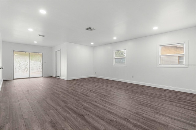 empty room with a wealth of natural light and dark hardwood / wood-style flooring