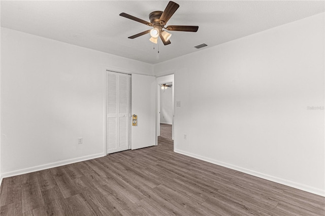 unfurnished bedroom with ceiling fan, a closet, and wood-type flooring