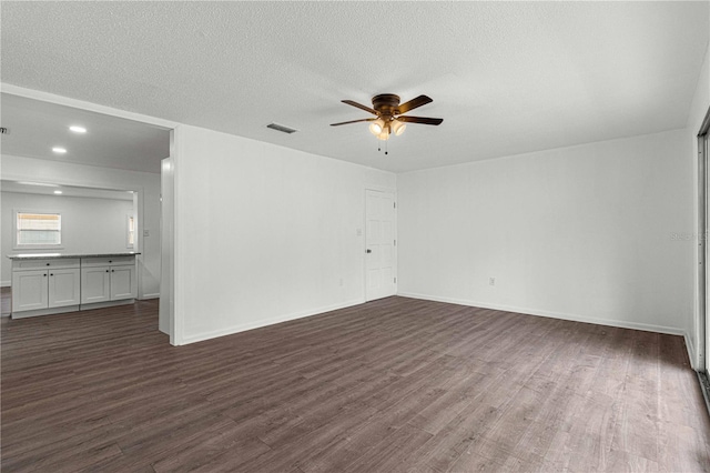 unfurnished living room with a textured ceiling, dark hardwood / wood-style floors, and ceiling fan