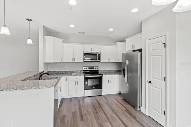 kitchen featuring hanging light fixtures, light hardwood / wood-style flooring, stainless steel appliances, kitchen peninsula, and light stone counters