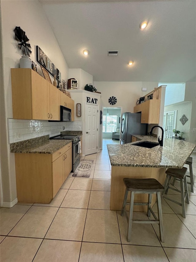 kitchen featuring kitchen peninsula, tasteful backsplash, stainless steel appliances, light tile floors, and sink