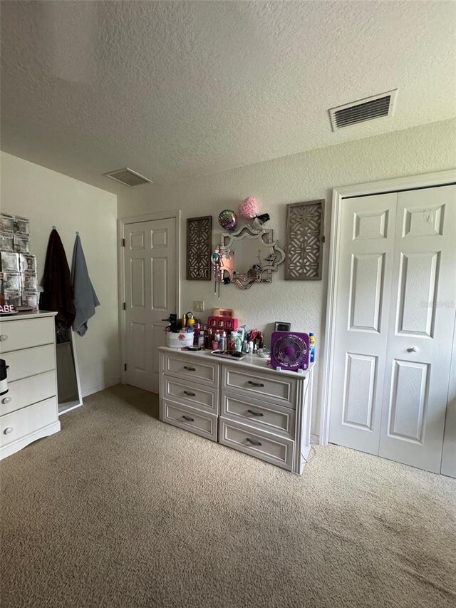 carpeted bedroom with a textured ceiling and a closet