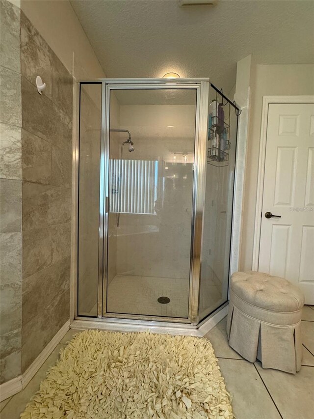 bathroom with an enclosed shower and tile flooring