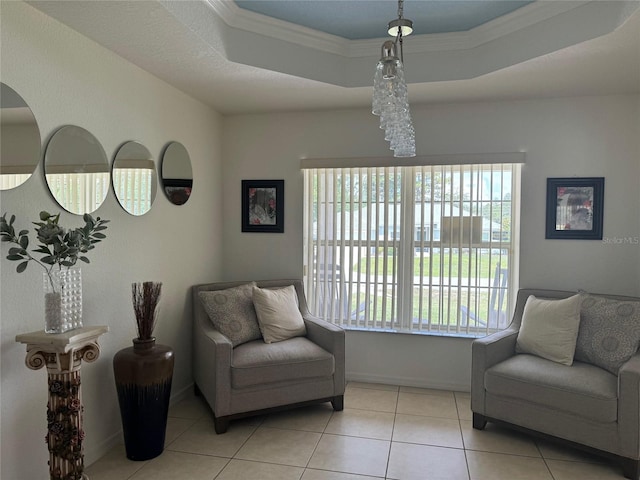 living area with plenty of natural light, ornamental molding, a tray ceiling, and light tile flooring